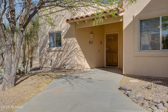 property entrance with a tile roof and stucco siding