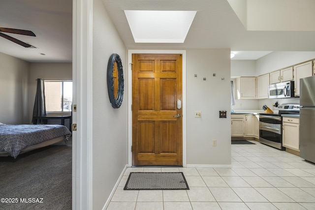 foyer with ceiling fan, baseboards, and light tile patterned flooring