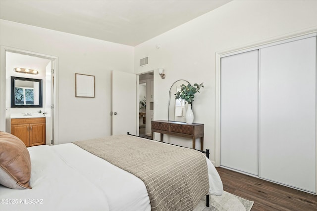 bedroom featuring a closet, visible vents, dark wood-type flooring, connected bathroom, and a sink