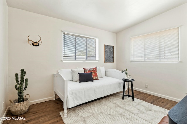 bedroom featuring lofted ceiling, baseboards, and wood finished floors