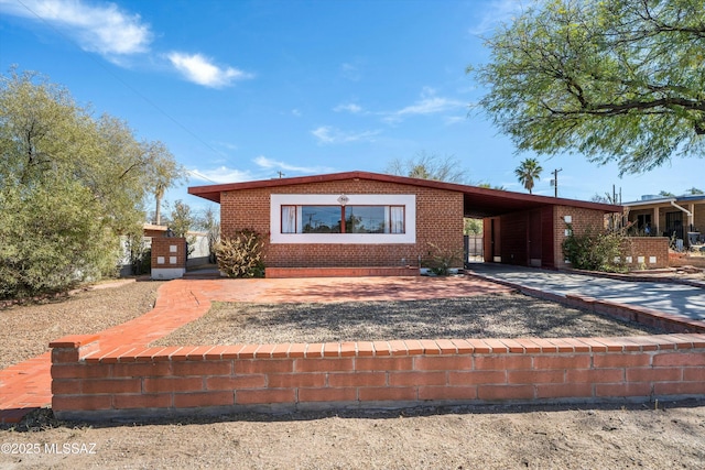 view of front of house featuring an attached carport, brick siding, and driveway