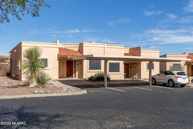 view of front of home featuring a tile roof, covered and uncovered parking, and stucco siding