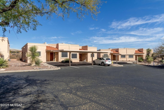 view of front facade featuring covered parking, a tiled roof, and stucco siding