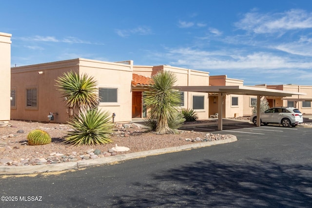 view of front of home featuring covered and uncovered parking, a tiled roof, and stucco siding