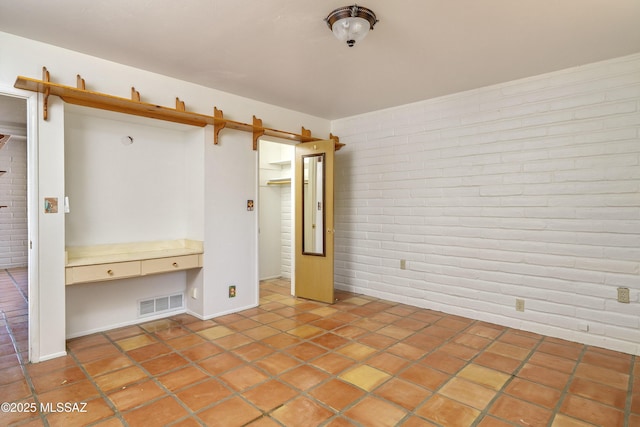 unfurnished bedroom featuring tile patterned floors, brick wall, and visible vents