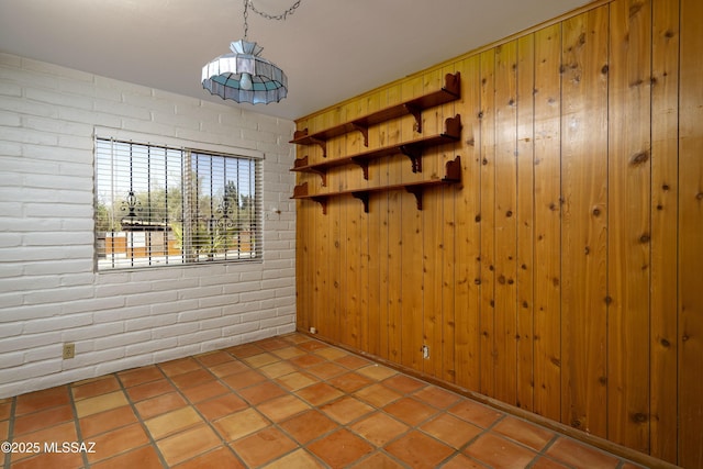 tiled empty room featuring brick wall and wooden walls
