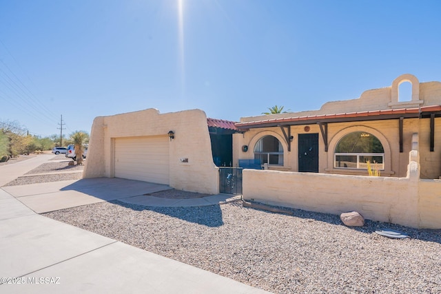 view of front facade with an attached garage, a fenced front yard, concrete driveway, and stucco siding