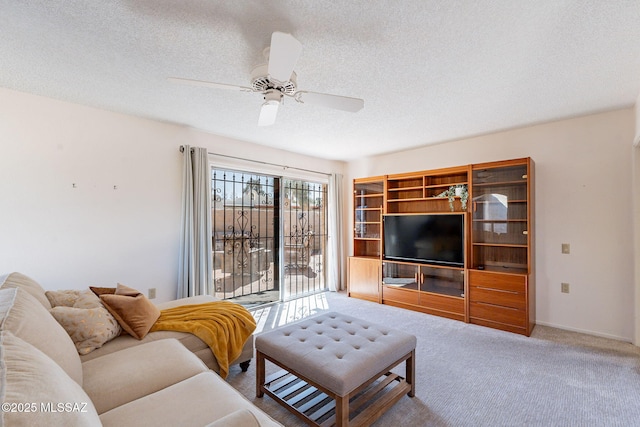 carpeted living area with ceiling fan, a textured ceiling, and baseboards