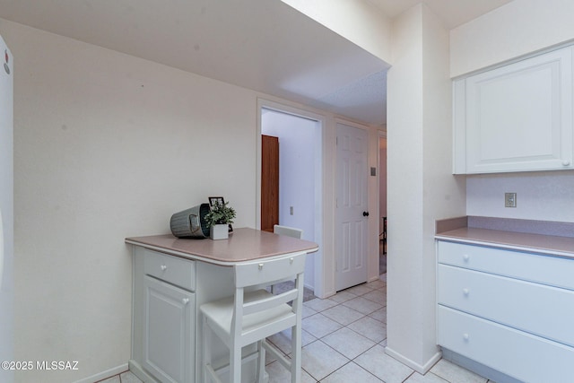 kitchen with baseboards, white cabinets, light countertops, and light tile patterned flooring