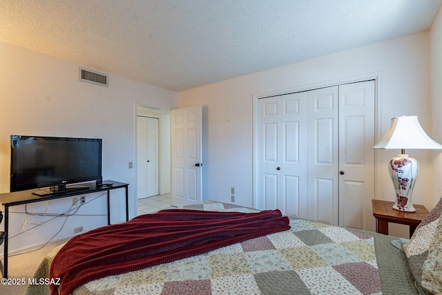 bedroom with a textured ceiling, visible vents, and multiple closets