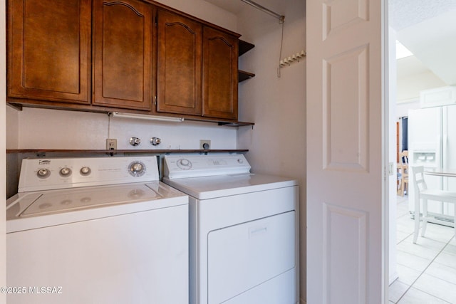 clothes washing area with light tile patterned flooring, cabinet space, and separate washer and dryer