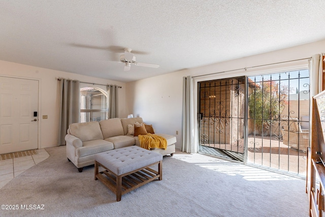 living room with light carpet, ceiling fan, and a textured ceiling