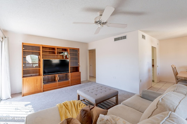 living room with a textured ceiling, visible vents, and light colored carpet