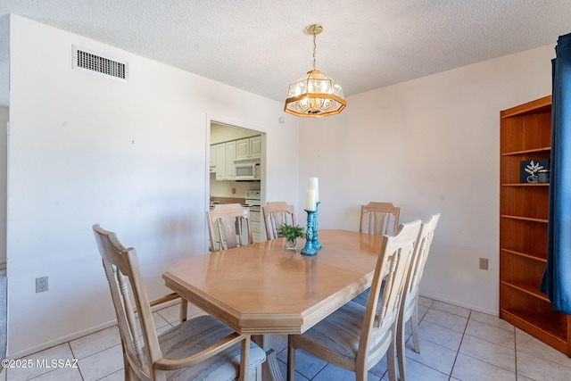 dining room featuring light tile patterned floors, visible vents, a chandelier, and a textured ceiling