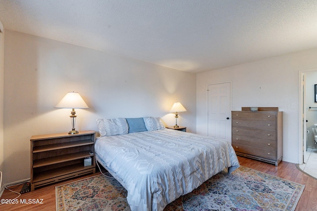 bedroom featuring a textured ceiling, wood finished floors, and ensuite bathroom