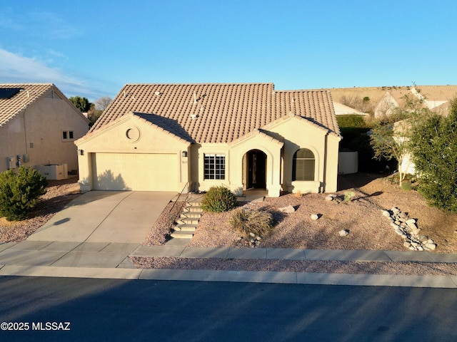 mediterranean / spanish house featuring driveway, an attached garage, a tile roof, and stucco siding