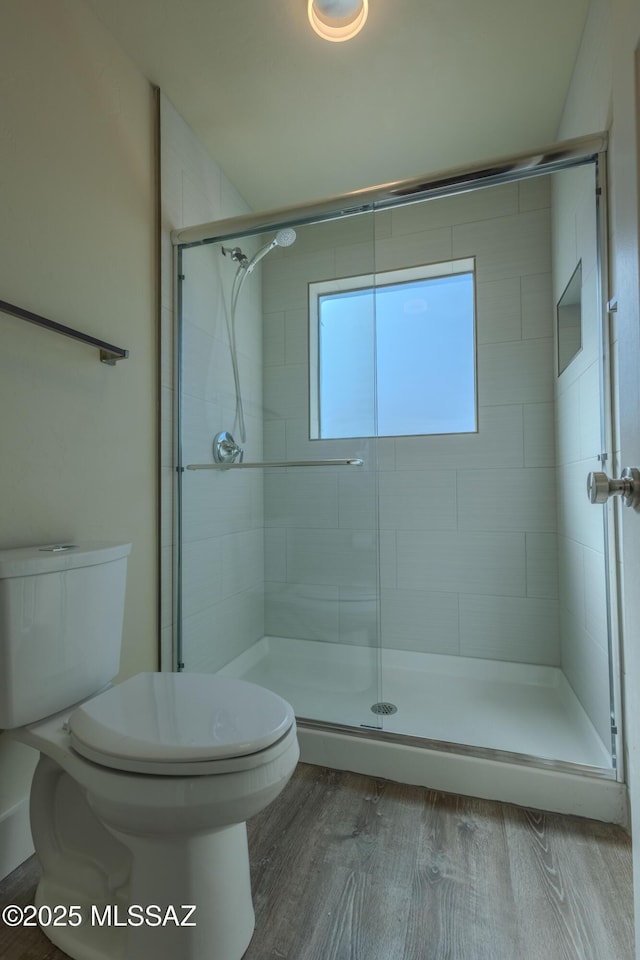 bathroom featuring toilet, a stall shower, and wood finished floors