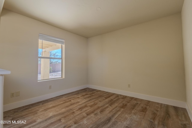 unfurnished room featuring baseboards and wood finished floors