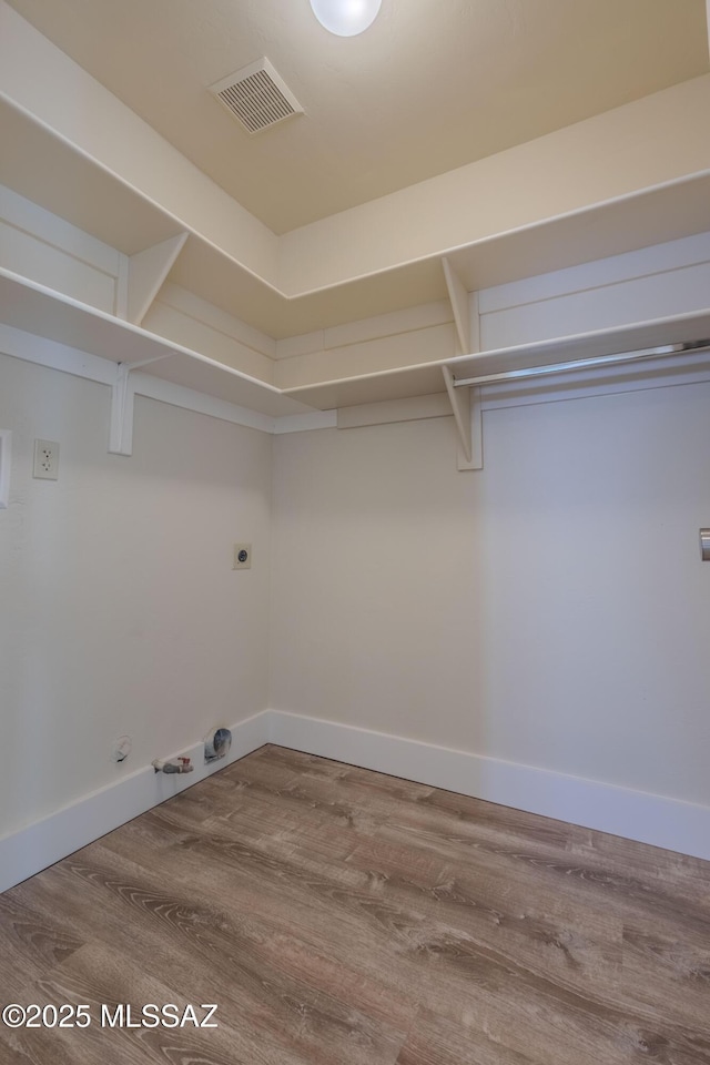 laundry room featuring visible vents, gas dryer hookup, wood finished floors, laundry area, and baseboards