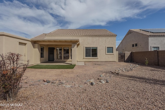 rear view of house featuring a patio area, fence, a tiled roof, and stucco siding