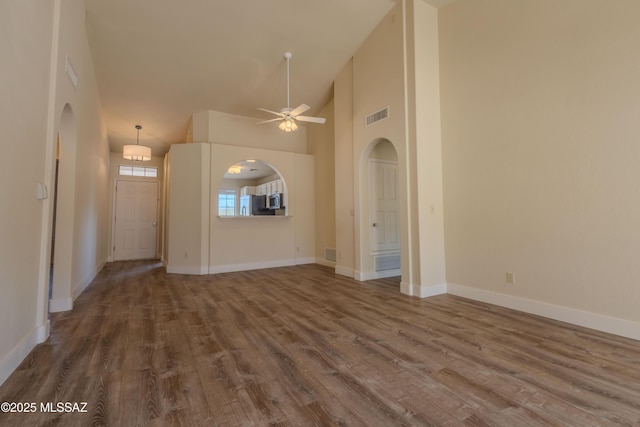 interior space with arched walkways, high vaulted ceiling, wood finished floors, and visible vents