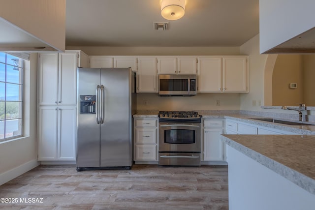 kitchen featuring light countertops, visible vents, appliances with stainless steel finishes, white cabinetry, and a sink