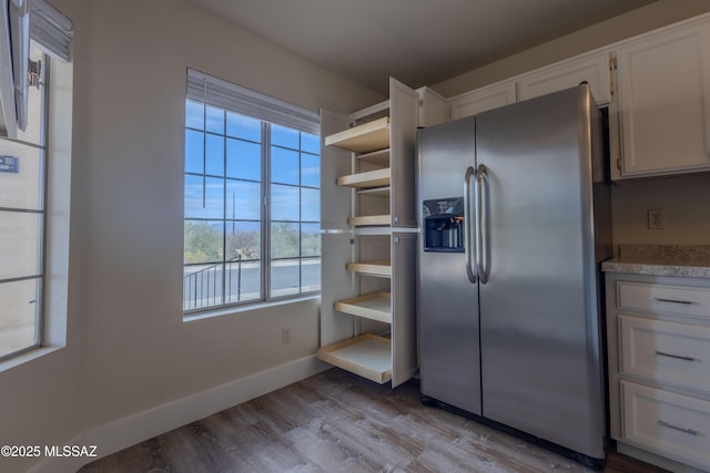 kitchen with white cabinetry, baseboards, light countertops, light wood finished floors, and stainless steel fridge