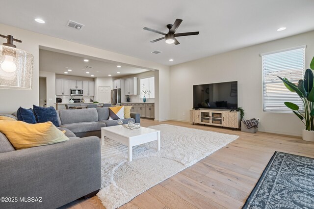 living room with light wood-style flooring, visible vents, and recessed lighting