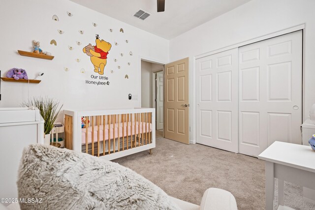 carpeted bedroom with a nursery area, a ceiling fan, and baseboards