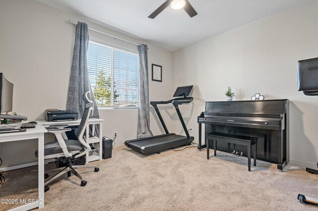 carpeted office space with a ceiling fan and baseboards