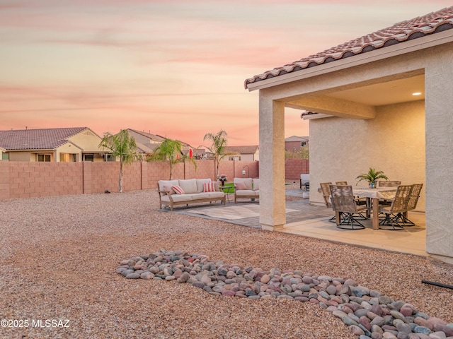 yard at dusk with a fenced backyard, a patio, and an outdoor hangout area