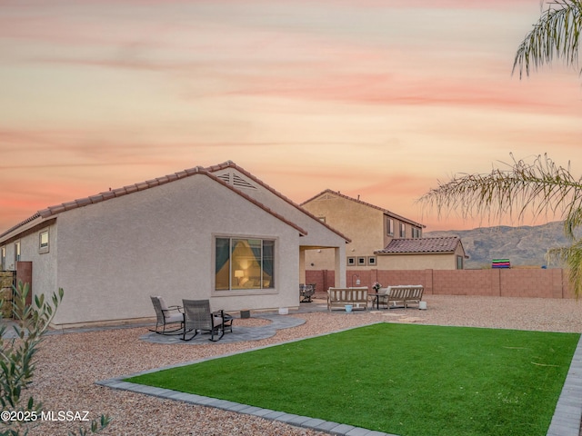 rear view of house with a yard, fence, a patio, and stucco siding