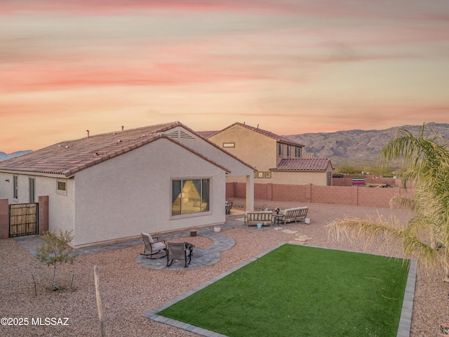 back of property with a patio, a fenced backyard, a yard, a mountain view, and stucco siding