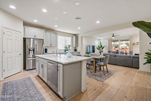 kitchen featuring light wood finished floors, a breakfast bar, stainless steel appliances, light countertops, and a sink