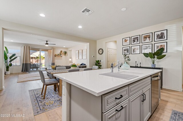 kitchen with stainless steel appliances, a healthy amount of sunlight, a sink, and an island with sink