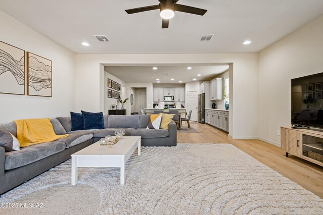 living area with a ceiling fan, recessed lighting, visible vents, and light wood finished floors