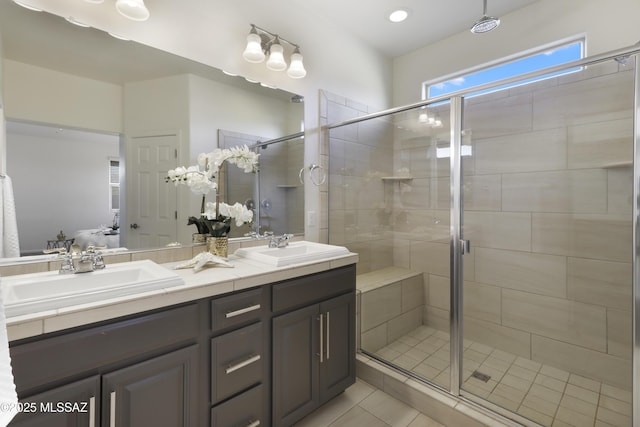 bathroom featuring double vanity, tile patterned flooring, a shower stall, and a sink