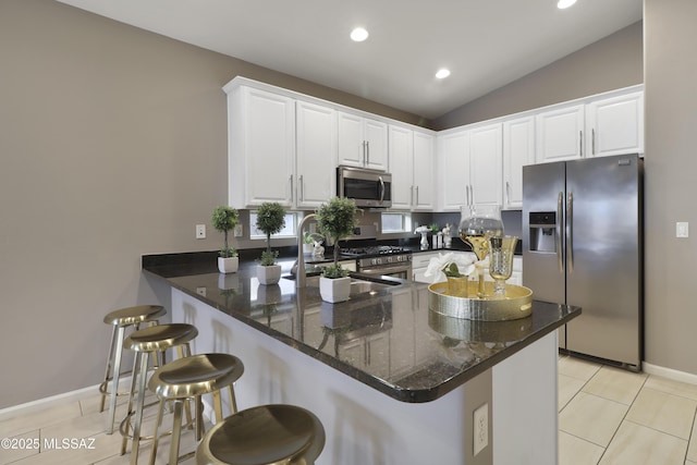 kitchen with white cabinets, lofted ceiling, a peninsula, stainless steel appliances, and light tile patterned flooring