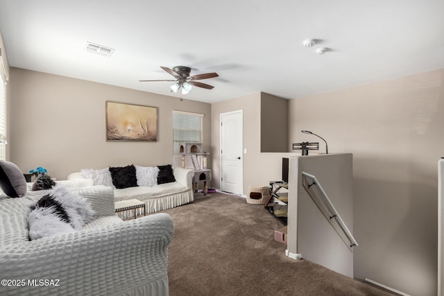 living area featuring ceiling fan, visible vents, and dark carpet