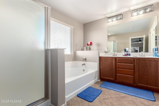 full bath with double vanity, a stall shower, tile patterned floors, a garden tub, and a sink