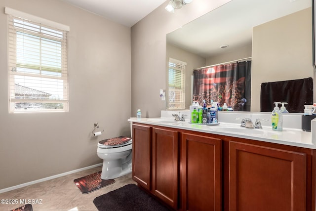 bathroom with toilet, tile patterned flooring, double vanity, and a sink