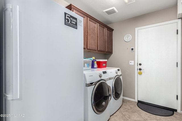 laundry area with visible vents, cabinet space, washing machine and dryer, light tile patterned flooring, and baseboards