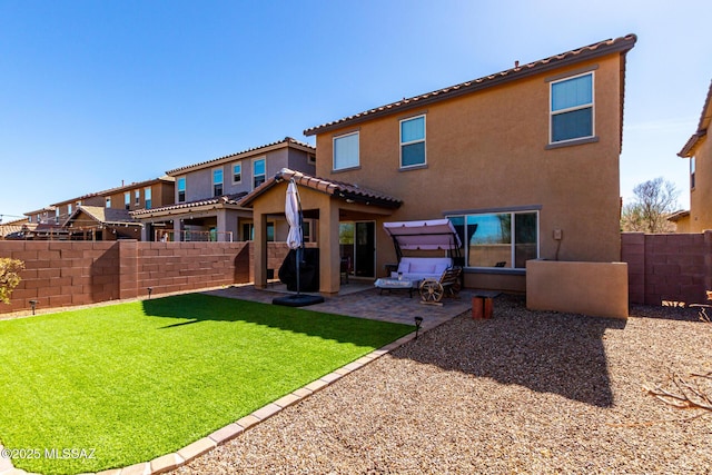 rear view of property featuring a patio, a lawn, a fenced backyard, and stucco siding