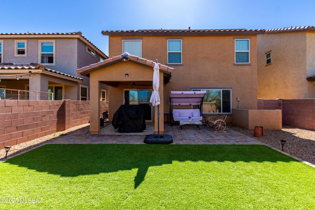 rear view of property featuring a patio area, a fenced backyard, a yard, and stucco siding