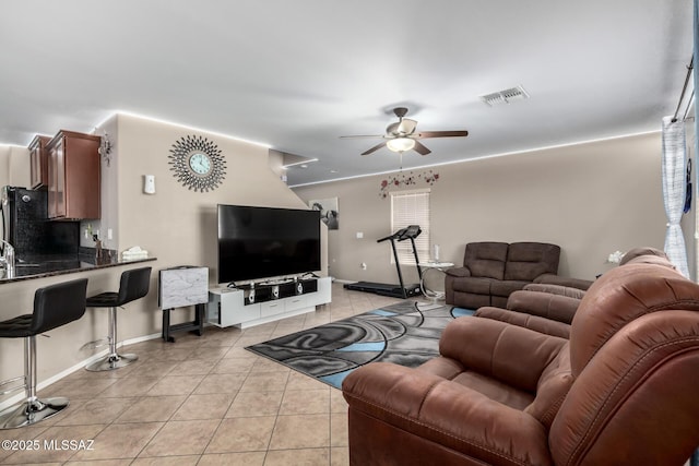 living area featuring light tile patterned floors, baseboards, visible vents, and a ceiling fan