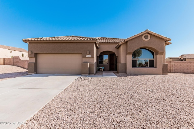 mediterranean / spanish home featuring concrete driveway, a tile roof, an attached garage, fence, and stucco siding