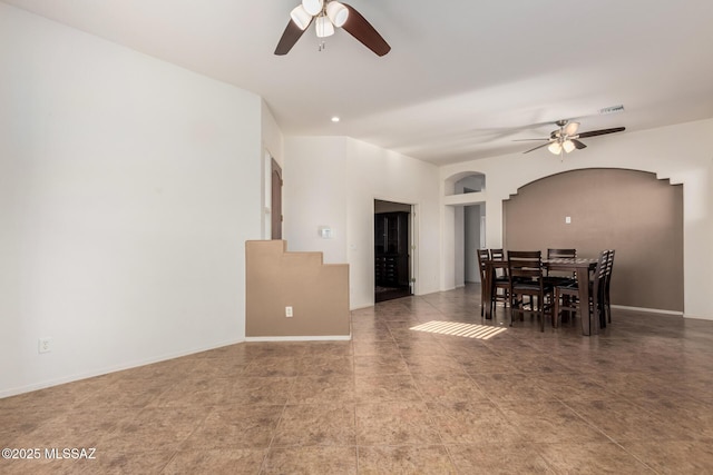 dining space with arched walkways, a ceiling fan, visible vents, and baseboards