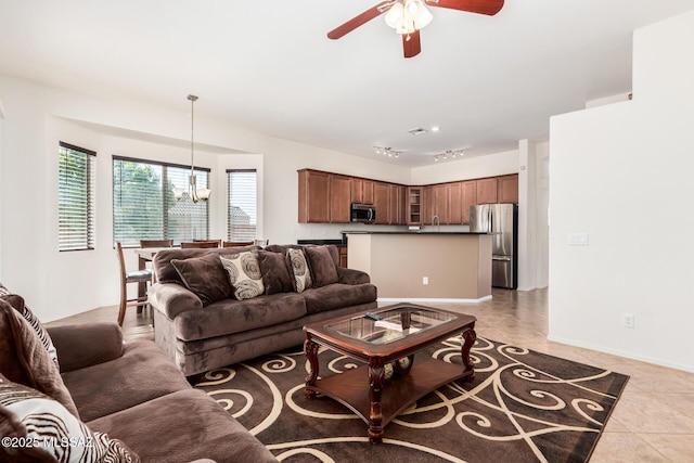 living area with light tile patterned floors, rail lighting, baseboards, and ceiling fan with notable chandelier