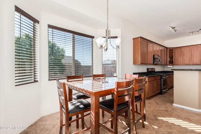 dining room with an inviting chandelier, light tile patterned floors, baseboards, and track lighting