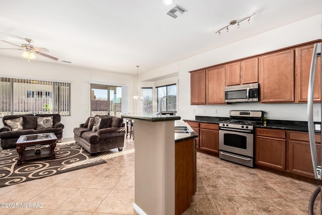 kitchen featuring pendant lighting, stainless steel appliances, dark countertops, visible vents, and open floor plan